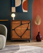 Credenza alta Marula in legno di acacia con intarsio nero in un soggiorno anni Sessanta rivisitato: parete verde petrolio, arco terracotta, pavimento in microcemento, poltrona in bouclé salvia e vaso bordeaux. Immagine di ambientazione generata con intelligenza artificiale: poltrona, vaso, lampada, quadro, tappeto e foglia di palma non sono compresi nella vendita