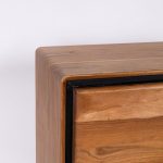 Dettaglio dello spigolo superiore arrotondato e del profilo nero perimetrale della credenza alta Marula in legno di acacia