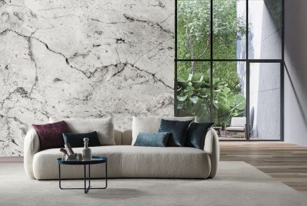 Divano Duepuntozero 260 cm in tessuto sfoderabile avorio, ambientato in un soggiorno con parete in marmo bianco, tavolino tondo scuro e cuscini decorativi nei toni bordeaux e blu petrolio
