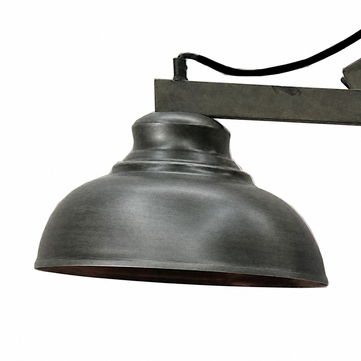 Dettaglio della cupola della lampada da terra Neptuno: campana in finitura argento anticata con collarino a gradini, fissata al braccio piatto; l’interno della cupola è di tonalità ramata e restituisce una luce calda. Cavo tessile nero. La lampadina non è compresa.