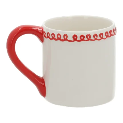 La stessa tazza vista dal lato opposto, con il corpo bianco liscio, il manico rosso e il festone di glassa rossa lungo il bordo.