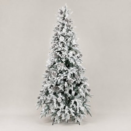 Albero di Natale artificiale Reykjavik alto 210 cm, fittamente innevato di bianco con pigne applicate tra i rami, montato su base a croce in metallo e fotografato su fondo neutro