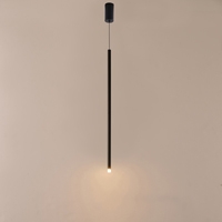 Lampada a sospensione Cascade a LED accesa davanti a una parete chiara, con il tubo nero sottile che porta la luce calda verso il basso