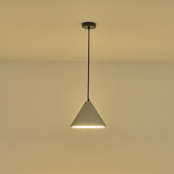 Lampada a sospensione Platre in cemento grigio plissettato, diametro 24 cm, accesa contro una parete chiara. La lampadina non è compresa