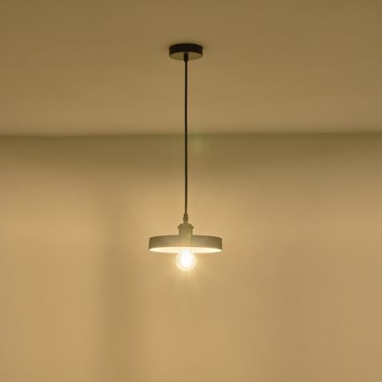 Lampada a sospensione Yeso in cemento grigio a disco, diametro 21 cm, accesa contro una parete chiara. La lampadina non è compresa