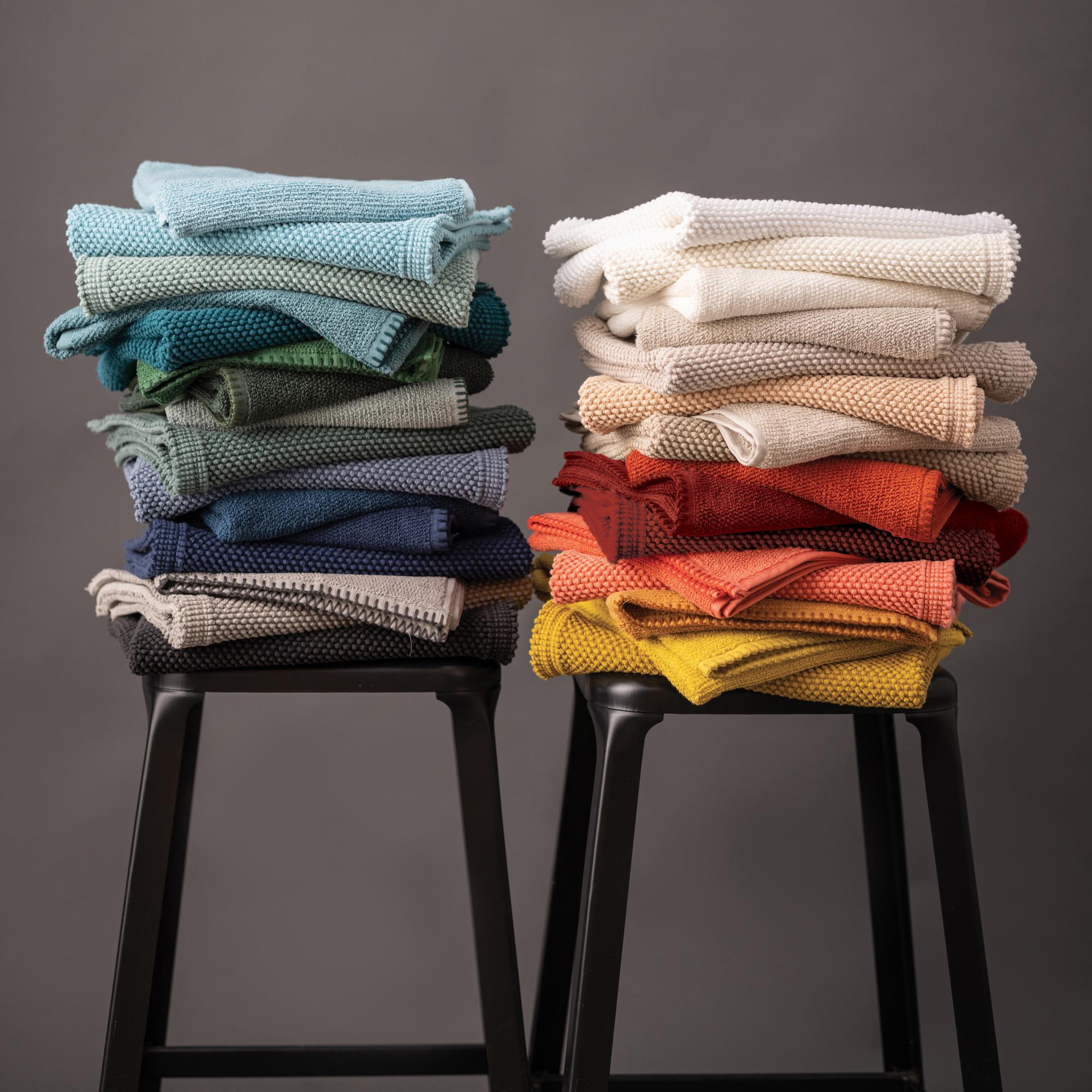 Tappeti da bagno Etia impilati in vari colori; sono compresi solo i colori in vendita su questa scheda