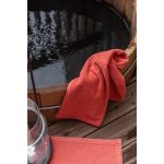 Asciugamano Bora color Corail appoggiato sul bordo di una vasca da bagno; gli altri oggetti della scena non sono compresi