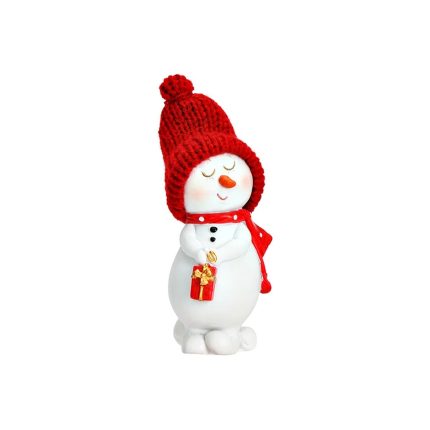 Pupazzo di neve in polyresina bianca su fondo bianco: berretto rosso in lana con pompon, sciarpa rossa a pois bianchi, occhi chiusi e naso a carota, due bottoni neri, tiene con le mani un pacchetto regalo rosso con il fiocco dorato.