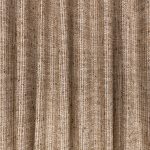 Il tessuto per tende Romo Veya nella colorazione Chocolate drappeggiato in pieghe morbide: marrone cioccolato, con filati bruni e sabbia intrecciati.