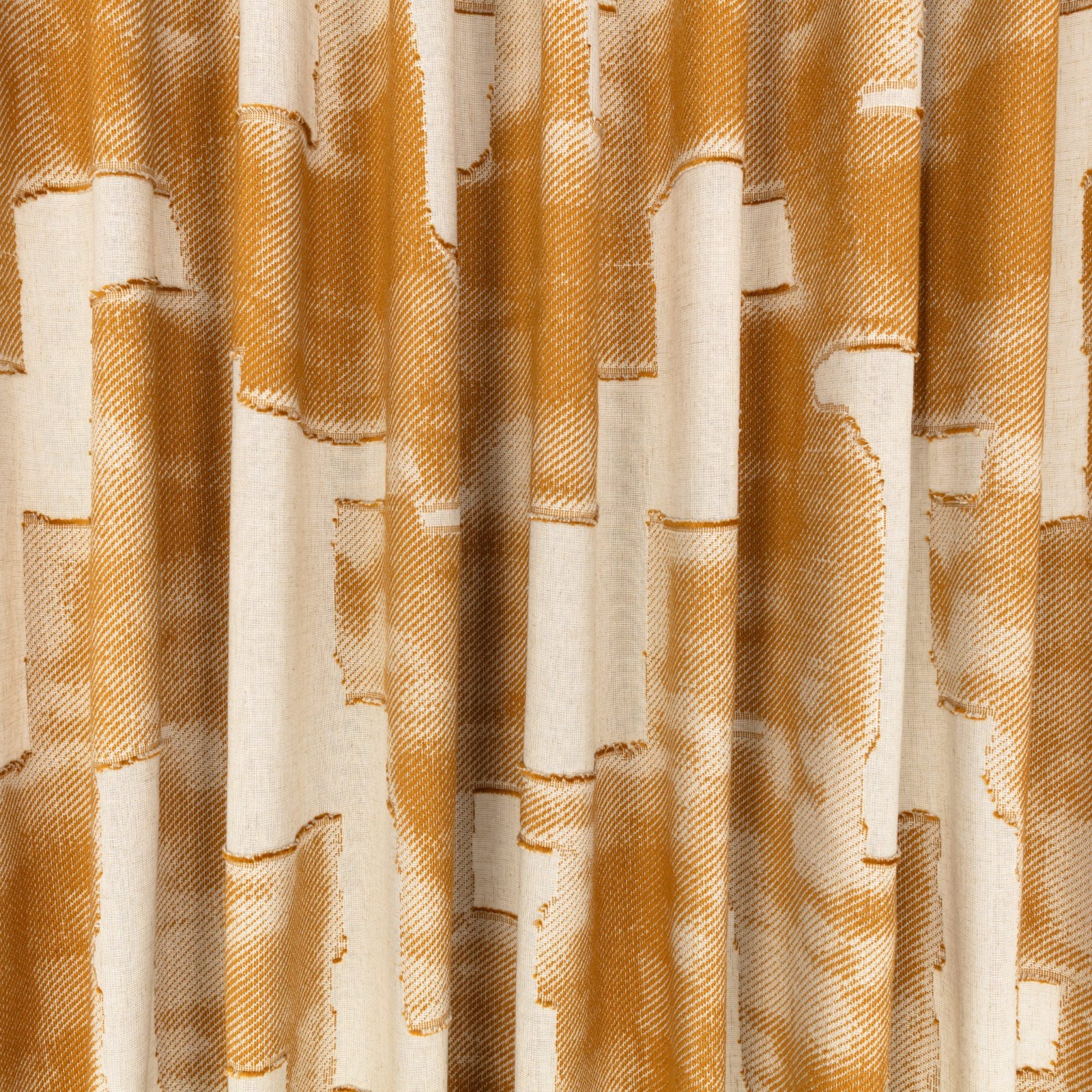 Il velo Idris di Villa Nova nella colorazione Sienna drappeggiato in pieghe morbide: forme geometriche ocra e arancio bruciato su fondo écru.