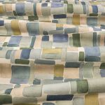 Il tessuto stampato in cotone e lino Nira di Villa Nova nella colorazione Cerulean drappeggiato in pieghe morbide: blocchi ad acquerello blu, verde salvia, oliva e sabbia su fondo écru.