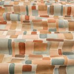 Il tessuto stampato in cotone e lino Nira di Villa Nova nella colorazione Sienna drappeggiato in pieghe morbide: blocchi ad acquerello terracotta, arancio, grigio azzurro e sabbia su fondo écru.