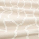 Il tessuto ricamato Samir di Villa Nova nella colorazione Birch drappeggiato in pieghe morbide: linee ricamate avorio e sabbia chiara, tono su tono su fondo écru.
