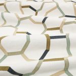 Il tessuto ricamato Samir di Villa Nova nella colorazione Mineral drappeggiato in pieghe morbide: linee ricamate sabbia, oliva, grigio salvia e antracite su fondo écru.